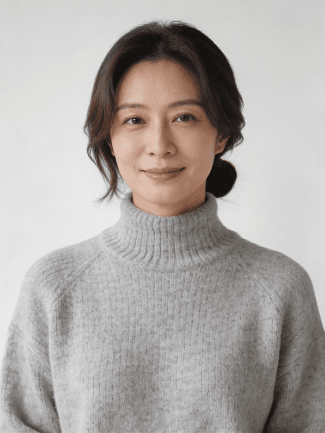 Portrait of a developer in a grey turtleneck against a pale wall